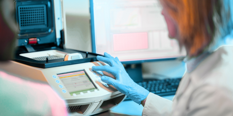A lab technician operating a qPCR machine