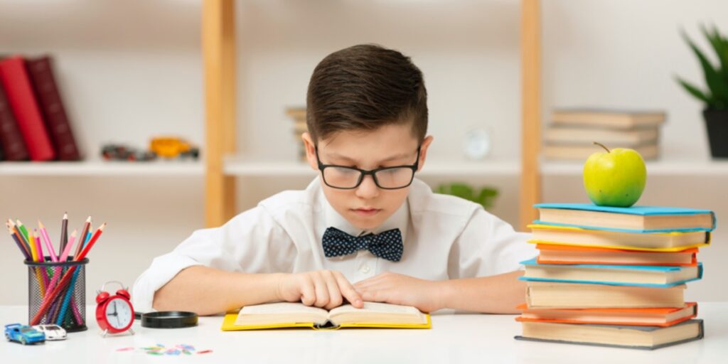 A picture of a young boy with a bow tie and glasses concentrating on reading a book to represent reading a scientific paper effectively