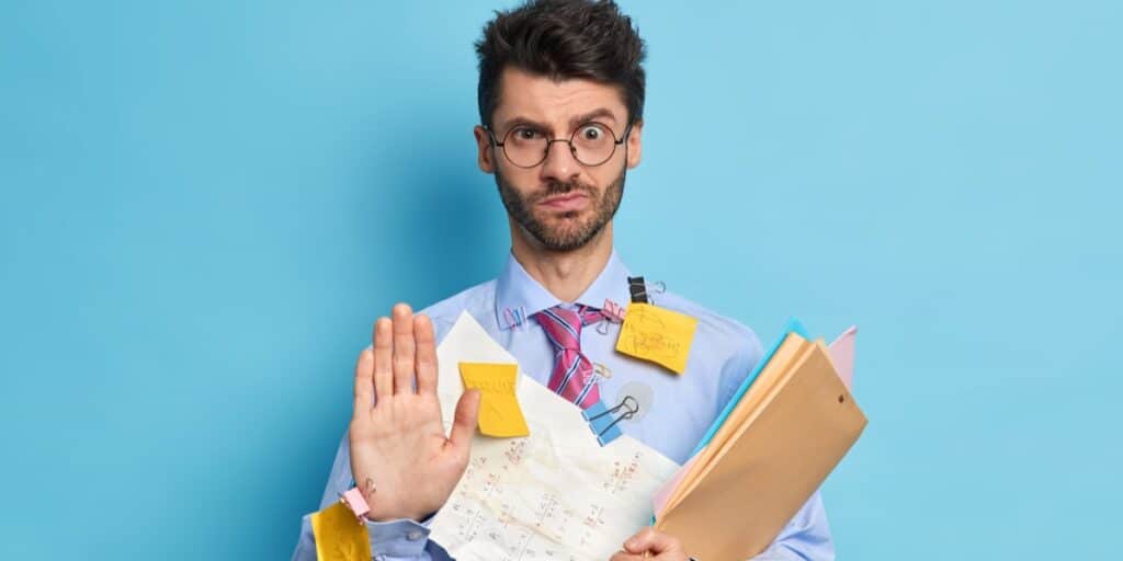 A bearded man dressed formally holding various documents and covered in sticky notes to represent getting started with reference managers for scientists