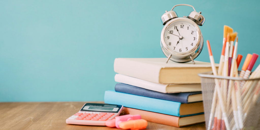 A clock on a stack of books to show how to read a scientific paper with limited time