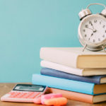 A clock on a stack of books to show how to read a scientific paper with limited time