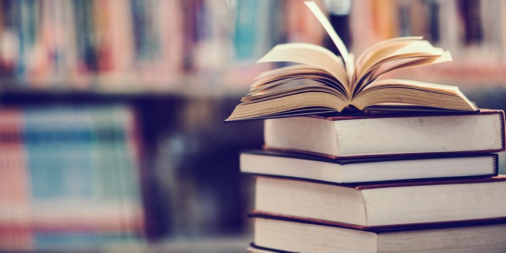 A pile of books with an open book on top to represent keeping track of the scientific literature