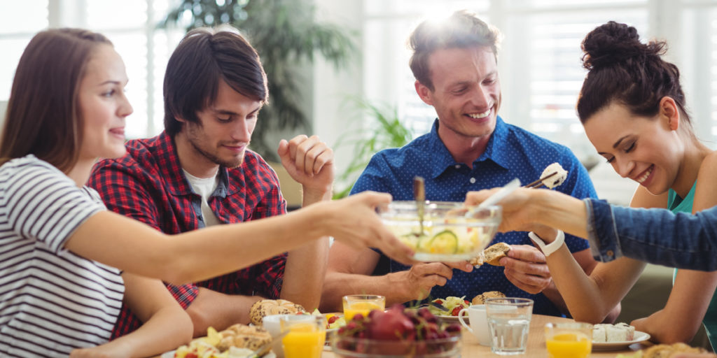 People sharing food around a table showing benefits of sharing resources