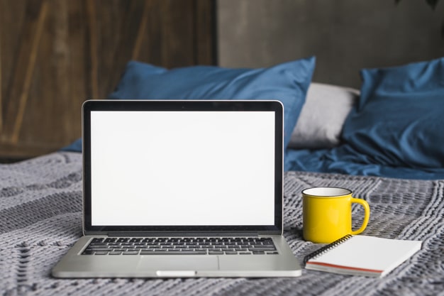 Computer and coffee on bed symbolizing working from home