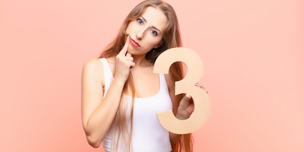 Woman holding numebr 3 looking confused, representing how unclear n numbers for cell line experiments are