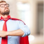 A man with a red tie and red cape standing proudly.