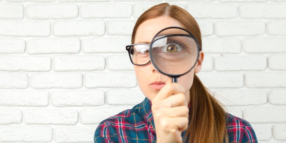 A woman holding a magnifying glass representing detecting post-translational modifications