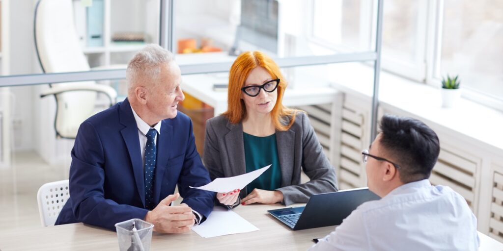 High angle view of two interviewers interviewing a young man to represent answering popular postdoc interview questions