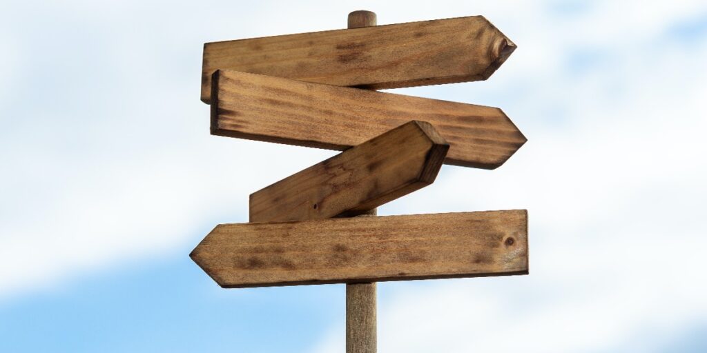 Picture of four empty wooden signs pointing in different directions to represent different life sciences career paths