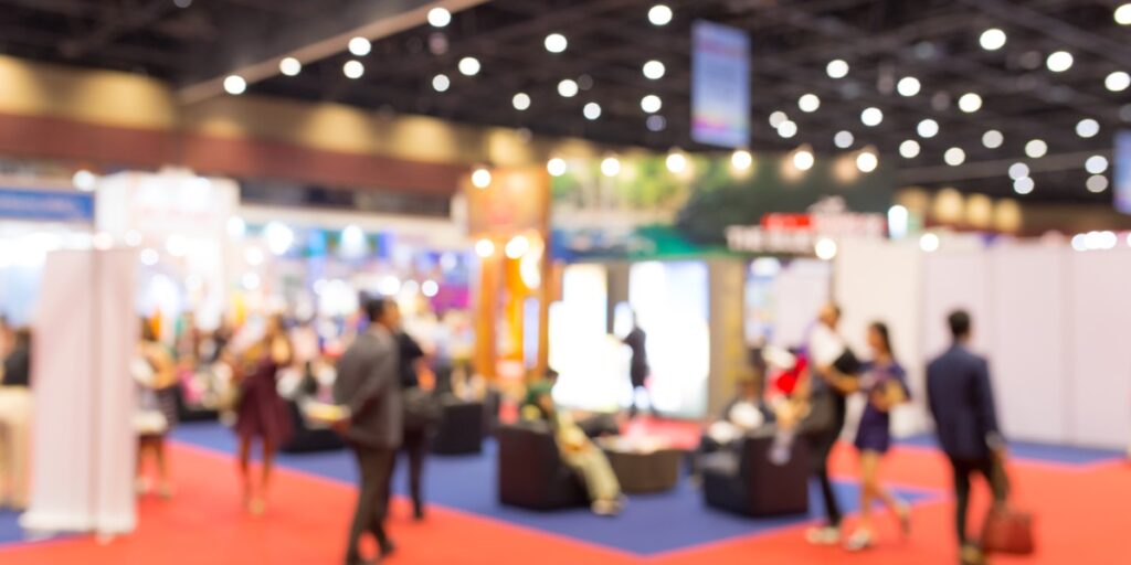 A blurred photograph of an event exhibition to represent a scientific conference and someone presenting a scientific research poster