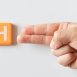 A scrabble-type tile showing a letter h next to a hand showing a sign language letter h to represent an author's h-index