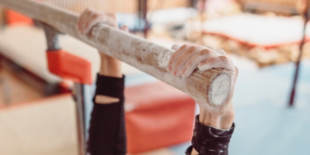 A gymnast's hands covered in chalk holding a gymnastics bar to represent tips to prevent sweaty glove hands during lab work