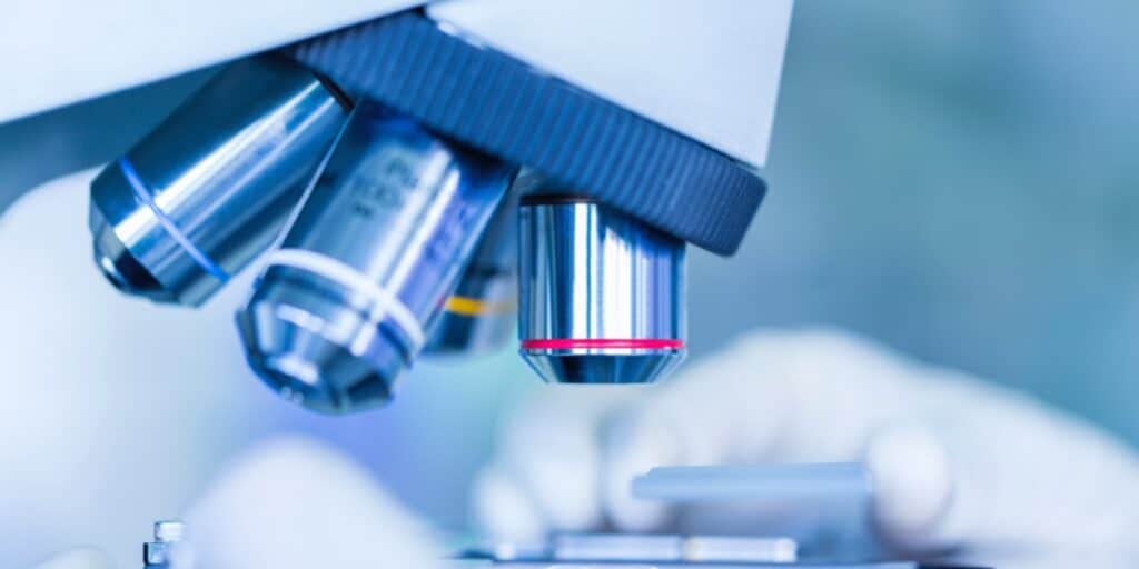 An image of microscope objectives with a scientist's hands to represent common microscope objective abbreviations