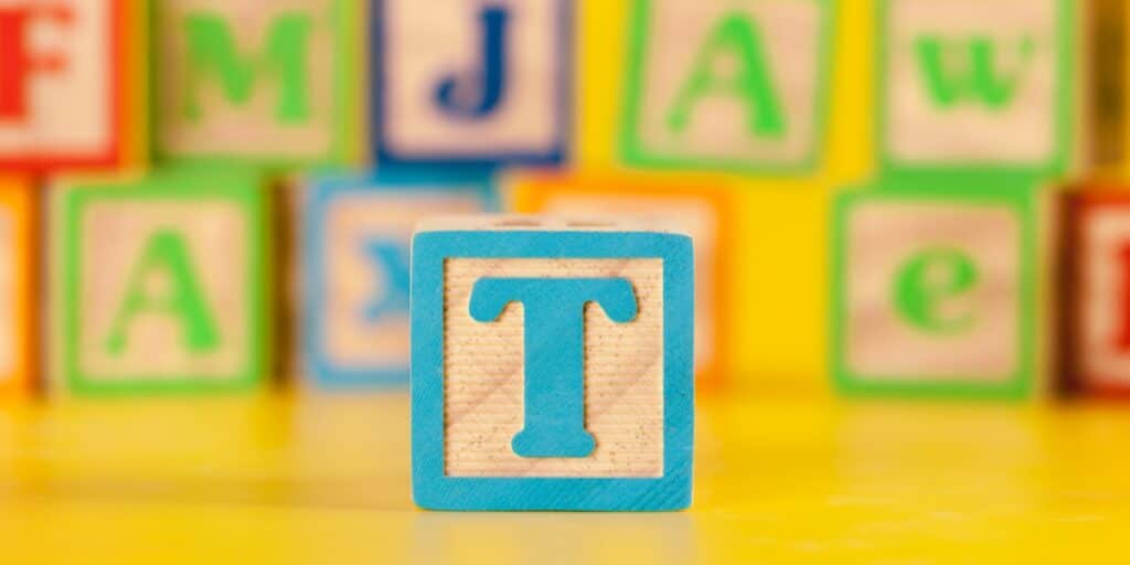 A wooden block with a letter t in front of several other blurred wooden blocks to represent the 3 Ts of introducing foreign DNA