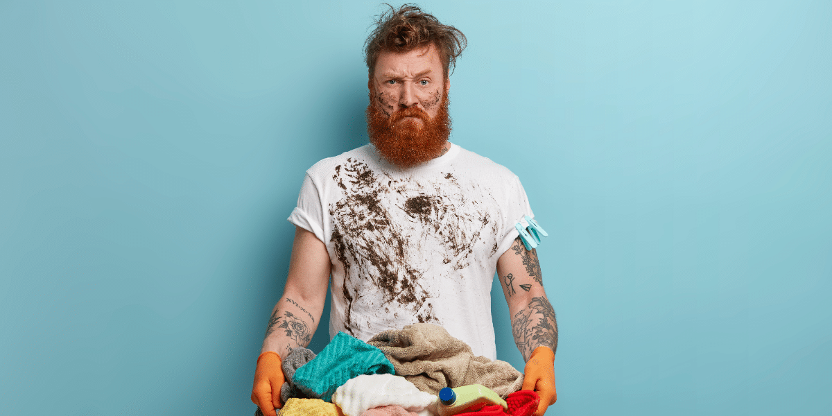 A bearded man with a stained top holding stained laundry to convey protein staining methods