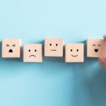 Five wooden blocks with different expressions from happy to sad to represent applying feedback for scientists