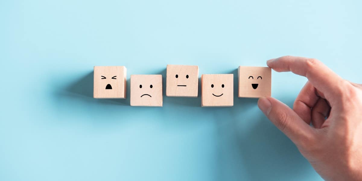 Five wooden blocks with different expressions from happy to sad to represent applying feedback for scientists