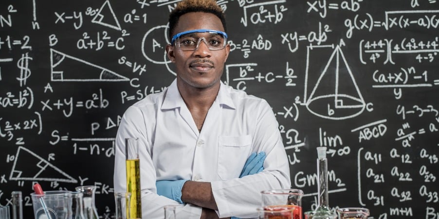 A researcher surrounded by numerous dangerous chemicals considering the 10 golden rules for working safely in the lab.