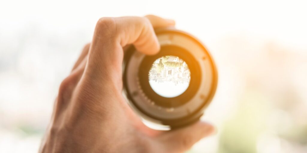 Man holding a lens up to the light to represent lenses and objectives