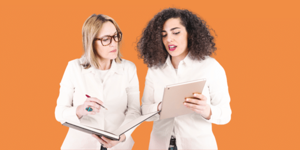 Two women discussing with tablet and notebook