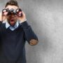 A picture of a man holding binoculars with a surprised expression to represent learning how to improve your PubMed searches